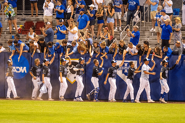 ISU baseball players give high-fives to crowd in the stadium during a game